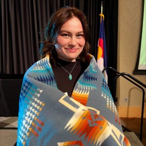 Zoe Mireles wrapped in a blanked with traditional Indigenous Native American pattern