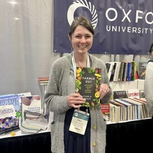 Professor Clare Brock holding her new book, Farmed Out